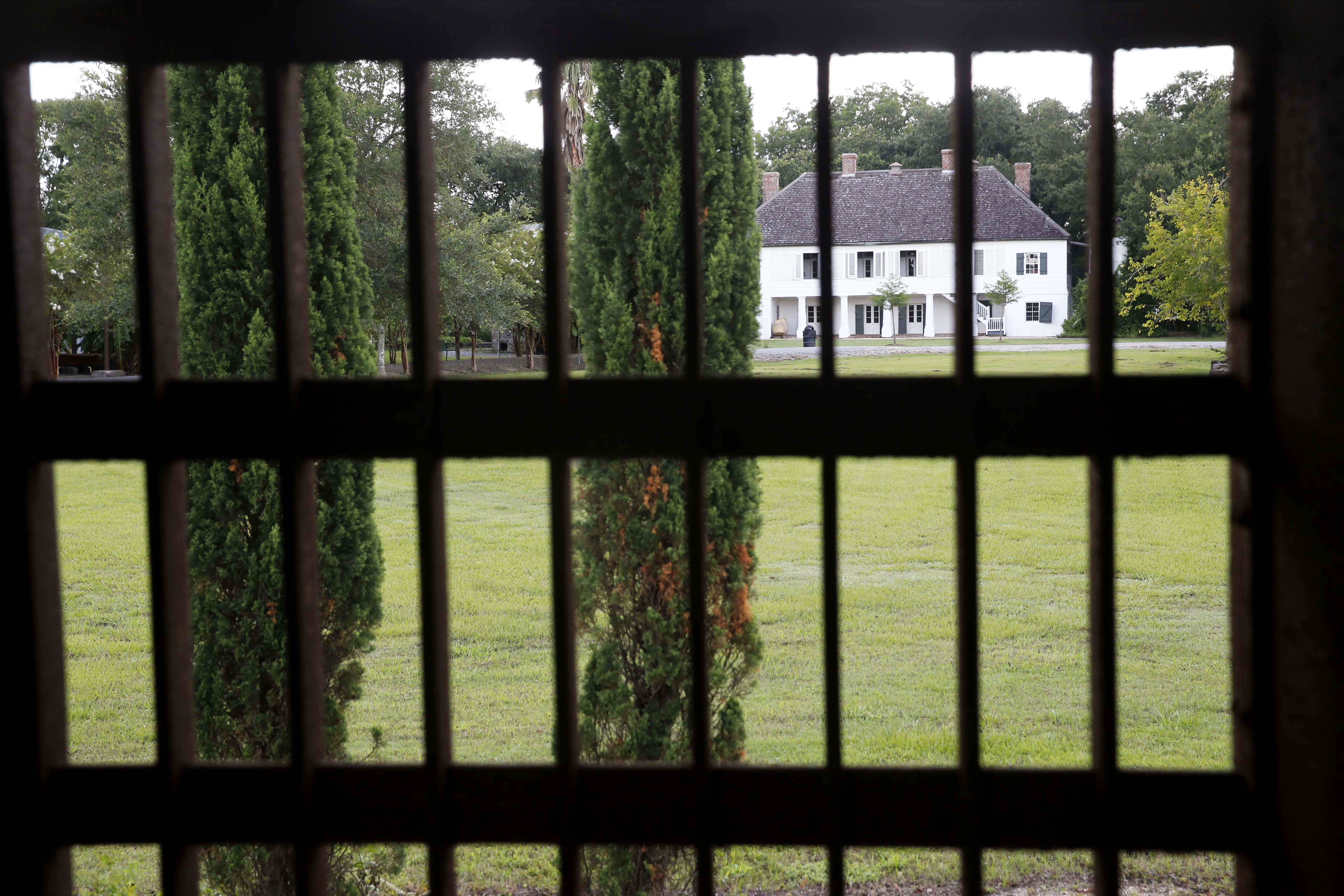 In this July 14, 2017 photo, the main plantation house is seen through the bars of a jail, similar to one&#039;s used for slaves, at the Whitney Plantation in Edgard, La. Owner John Cummings opened Whitney in 2014 as a slavery museum, bucking a tradition of plantation tours that romanticize antebellum life and gloss over the slave trade.<br />(Gerald Herbert / AP Photo)