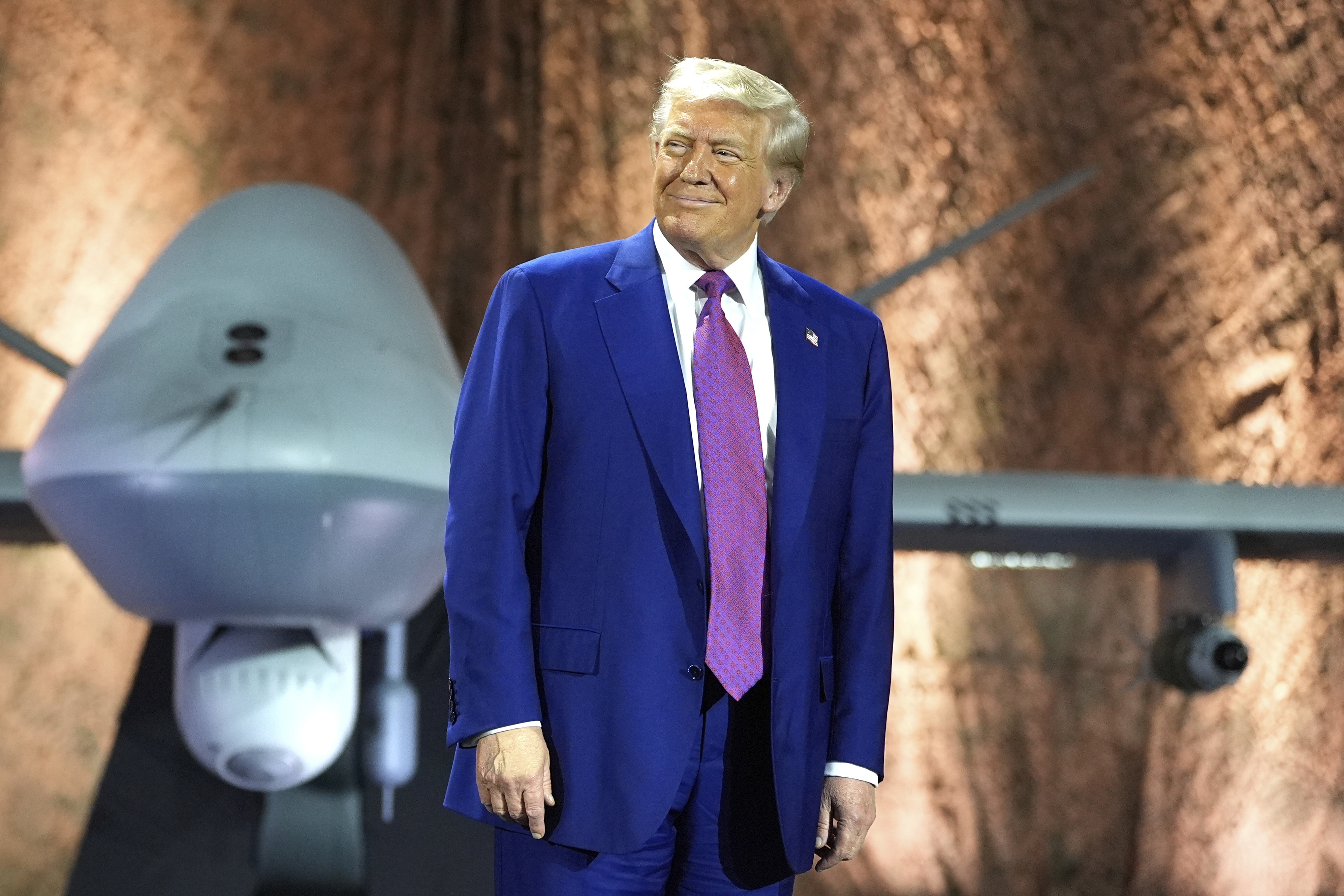 President Donald Trump smiles backdropped by an MQ-9 Reaper drone before addressing military personnel at the Al Udeid Air Base, Thursday, May 15, 2025, in Doha, Qatar.<br />(Alex Brandon / AP Photo)