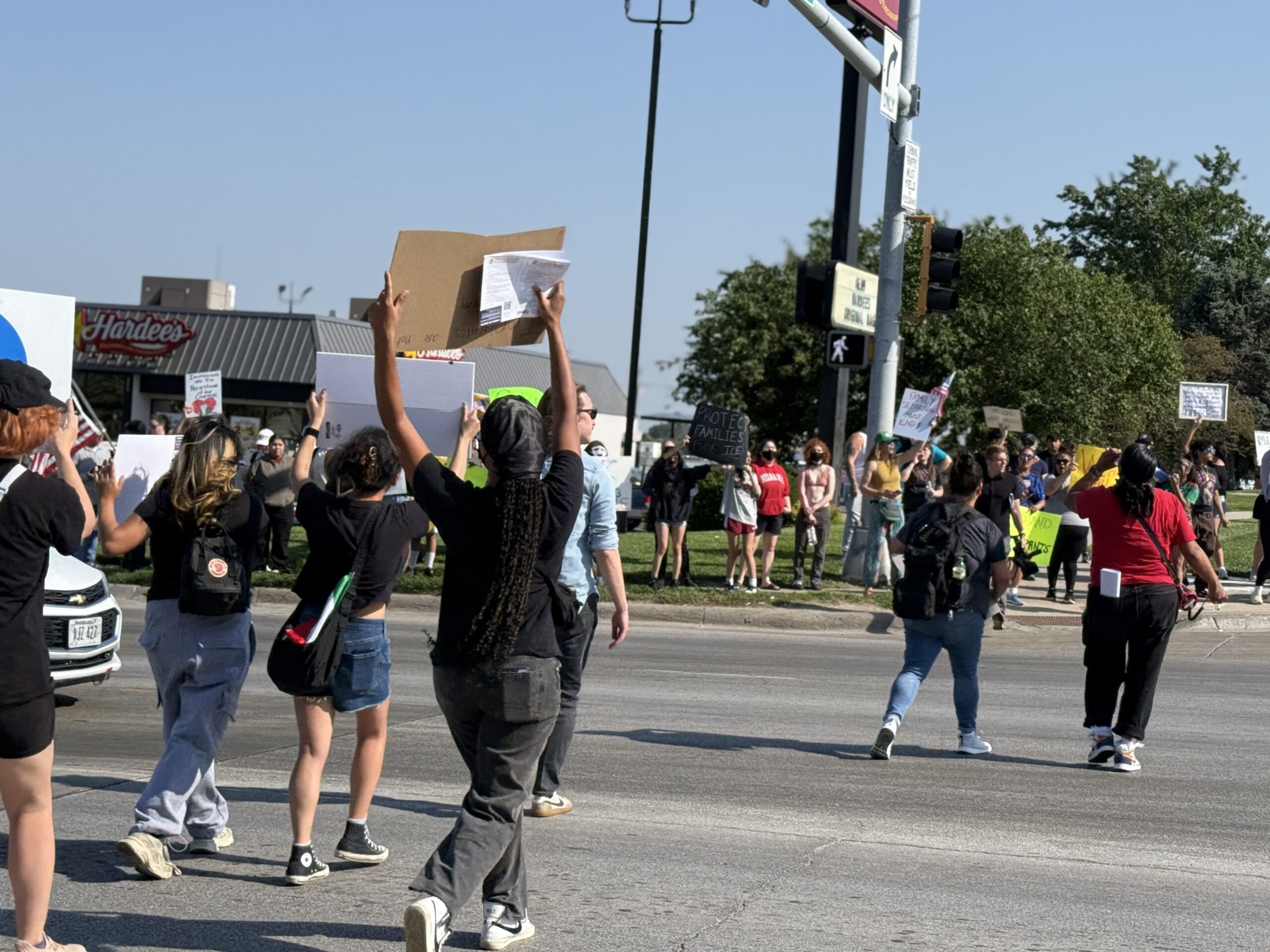 Protesters wave signs and chant near 33rd and L Streets in Omaha on Tuesday after a raid of an Omaha-area food plant.<br />(Cindy Gonzalez / Nebraska Examiner)