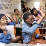 Ceteria Matthews (left) and Teyrr Bynum raise their hands during a game meant to teach about pregnancy and postpartum nutrition as part of I Be Black Girl’s Doula Passage Program.
 (Rebecca S. Gratz / Flatwater Free Press)