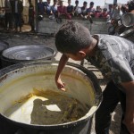 A boy scrapes leftovers from an empty pot after all the meals were distributed at a community kitchen in Khan Younis, southern Gaza Strip, Wednesday, May 14, 2025. 
(Abdel Kareem Hana / AP Photo)