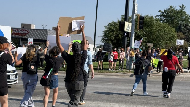 Protesters wave signs and chant near 33rd and L Streets in Omaha on Tuesday after a raid of an Omaha-area food plant. 
(Cindy Gonzalez / Nebraska Examiner)