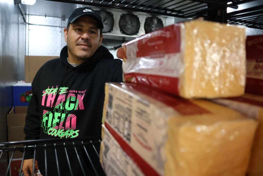 Tristan Runnels checks out commodity cheese at the Santee tribal food distribution center. The cheese evokes nostalgia from older tribe members who lived through a period when commodity foods were notoriously unhealthy.<br />(Tim Trudell / Flatwater Free Press)