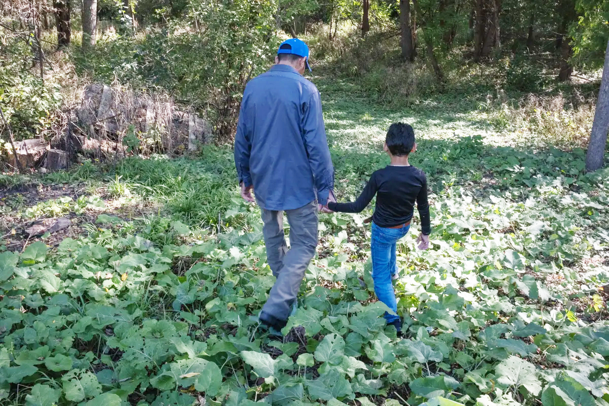 Ariel and his 7-year-old son walk down to the woods next to their home.<br />(Sofia Aldinio / ProPublica)