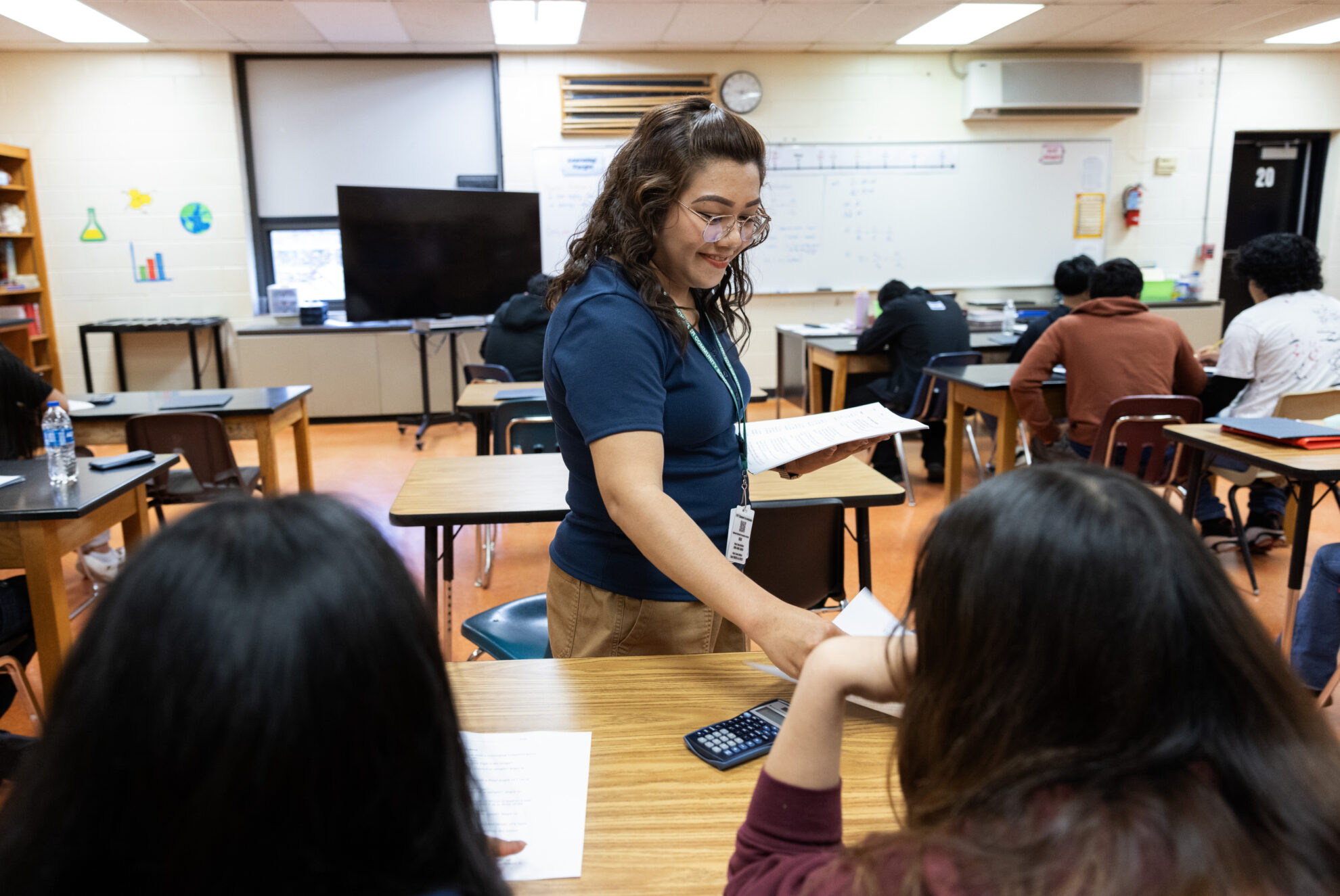 Dorina Ramos passes out a worksheet while teaching a lesson in a physical science class in Schuyler, Neb., on May 2, 2025. A group of teachers from the Philippines moved to Schuyler to teach under H-1B visas this year.<br />(Rebecca S. Gratz / Flatwater Free Press)