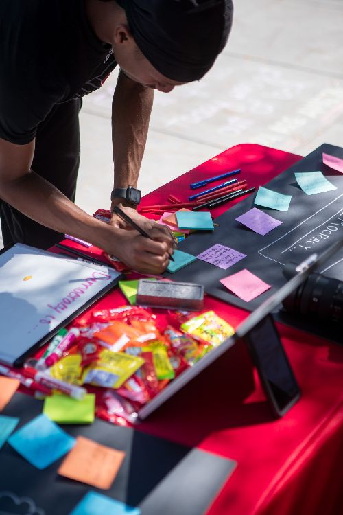 A UNL student writes what democracy means to them on a sticky note outside the Nebraska Union at a booth conducted by SPJ-UNL President, Zach Wendling. (Sammy Smith / NNS)