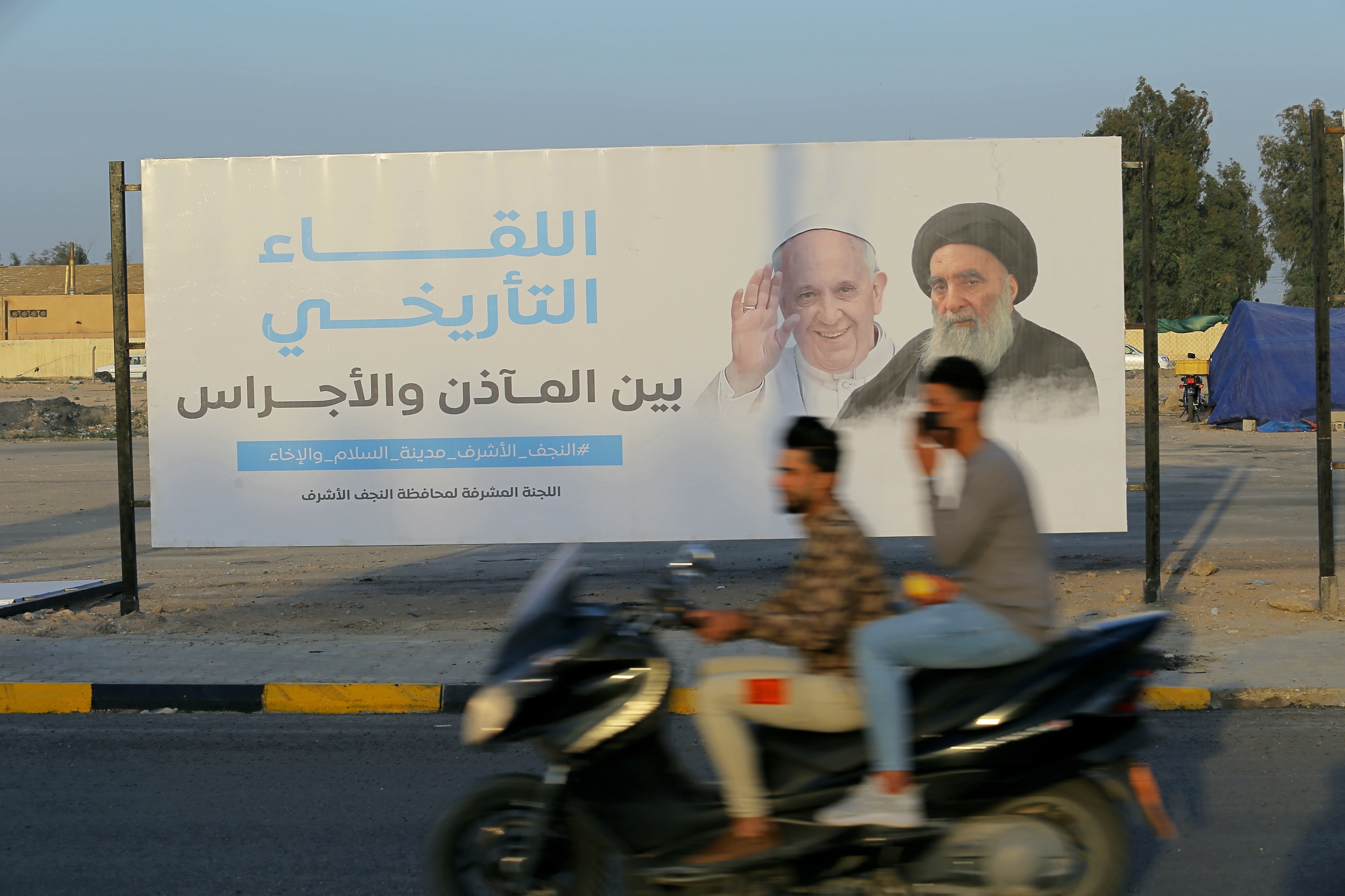 Iraqis put up a poster with Pope Francis and Grand Ayatollah Ali al-Sistani, the leader of Iraqi Shiite Muslims, in Najaf, Iraq, on March 4, 2021.<br />(Anmar Khalil / AP Photo)