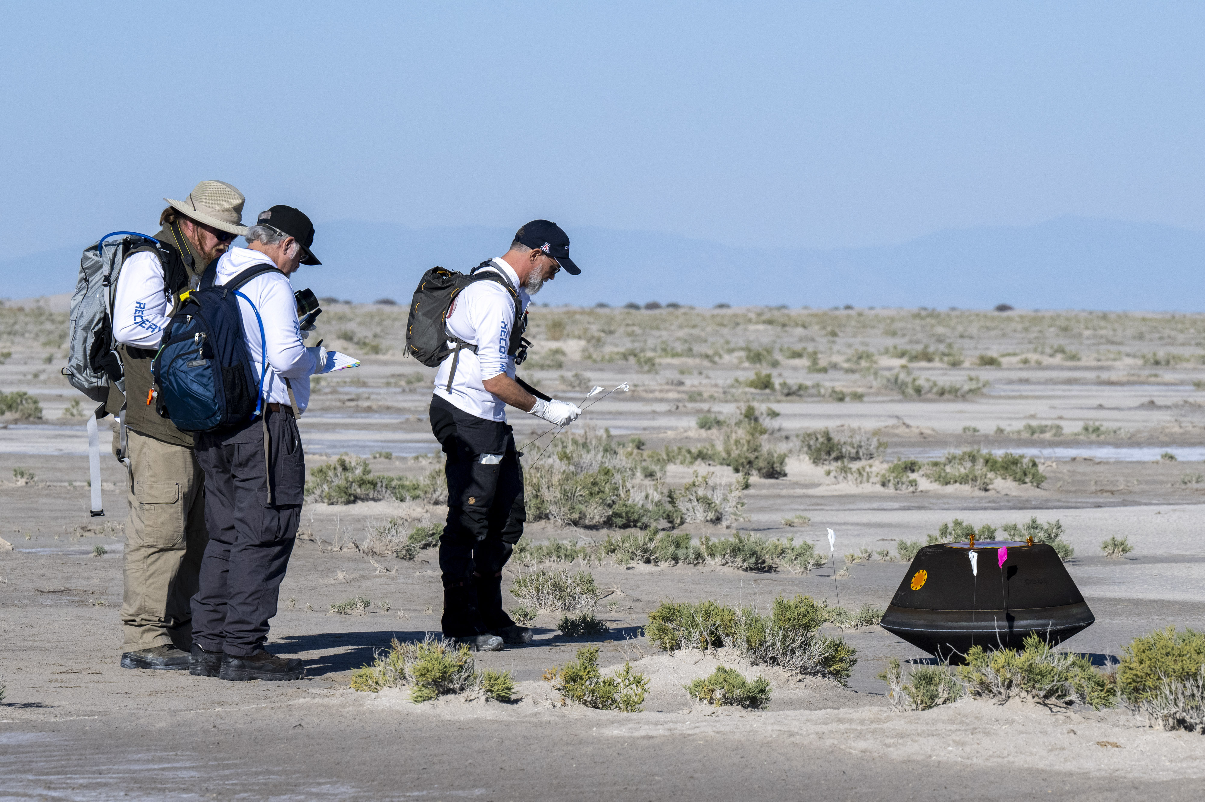 In this photo provided by NASA, from left, NASA Astromaterials Curator Francis McCubbin, NASA Sample Return Capsule Science Lead Scott Sandford and University of Arizona Osiris-Rex Principal Investigator Dante Lauretta, collect data next to the sample return capsule from NASA&#039;s Osiris-Rex mission after it landed at the Department of Defense&#039;s Utah Test and Training Range on Sunday, Sept. 24, 2023.<br />(Keegan Barber / NASA via AP)