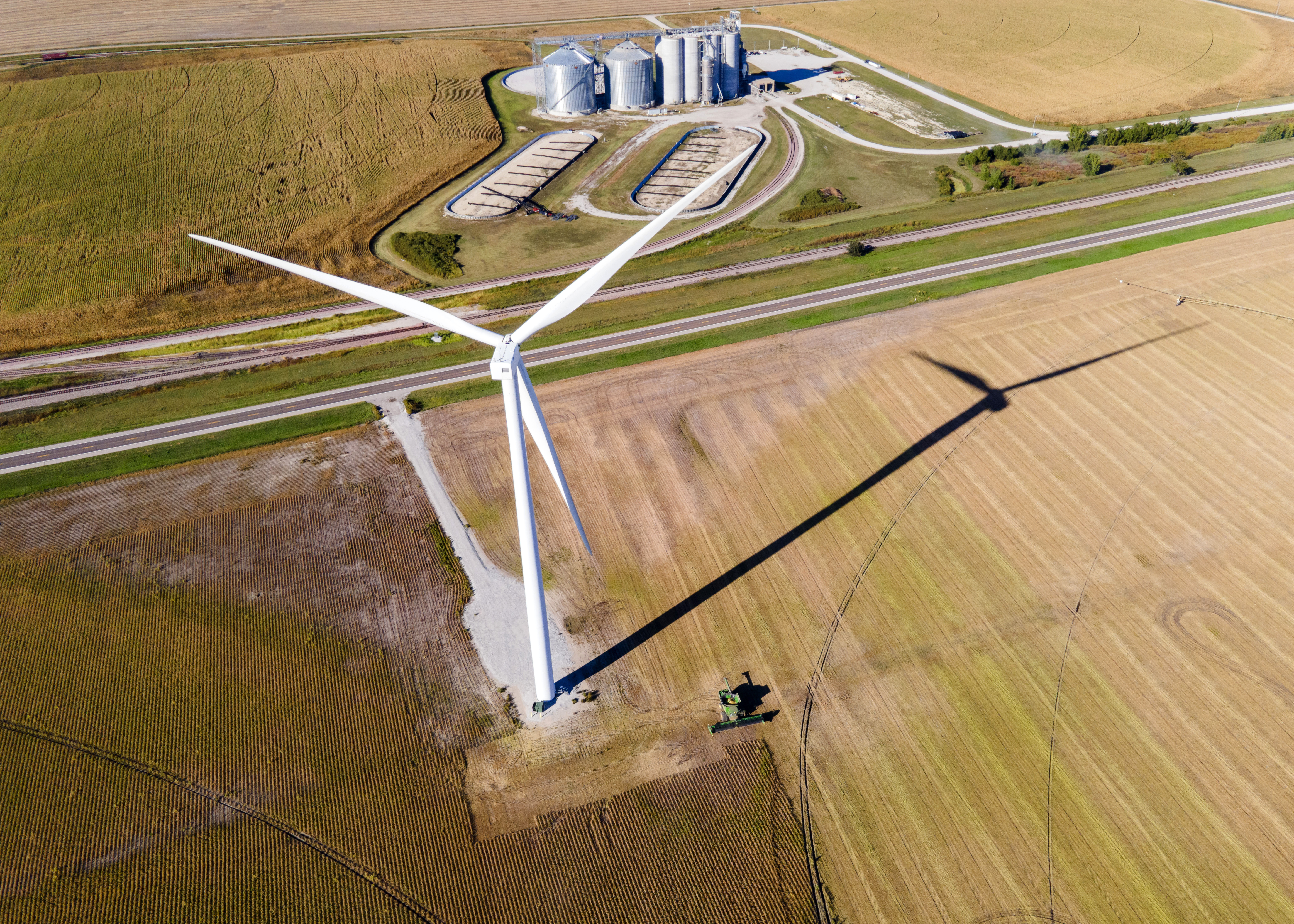 A farmer harvests a crop of soybeans using a combine just beneath a wind turbine, just west of Fairmont, Neb., on Tuesday, Sept. 26, 2023.<br />(Kenneth Ferriera / Lincoln Journal Star via AP)