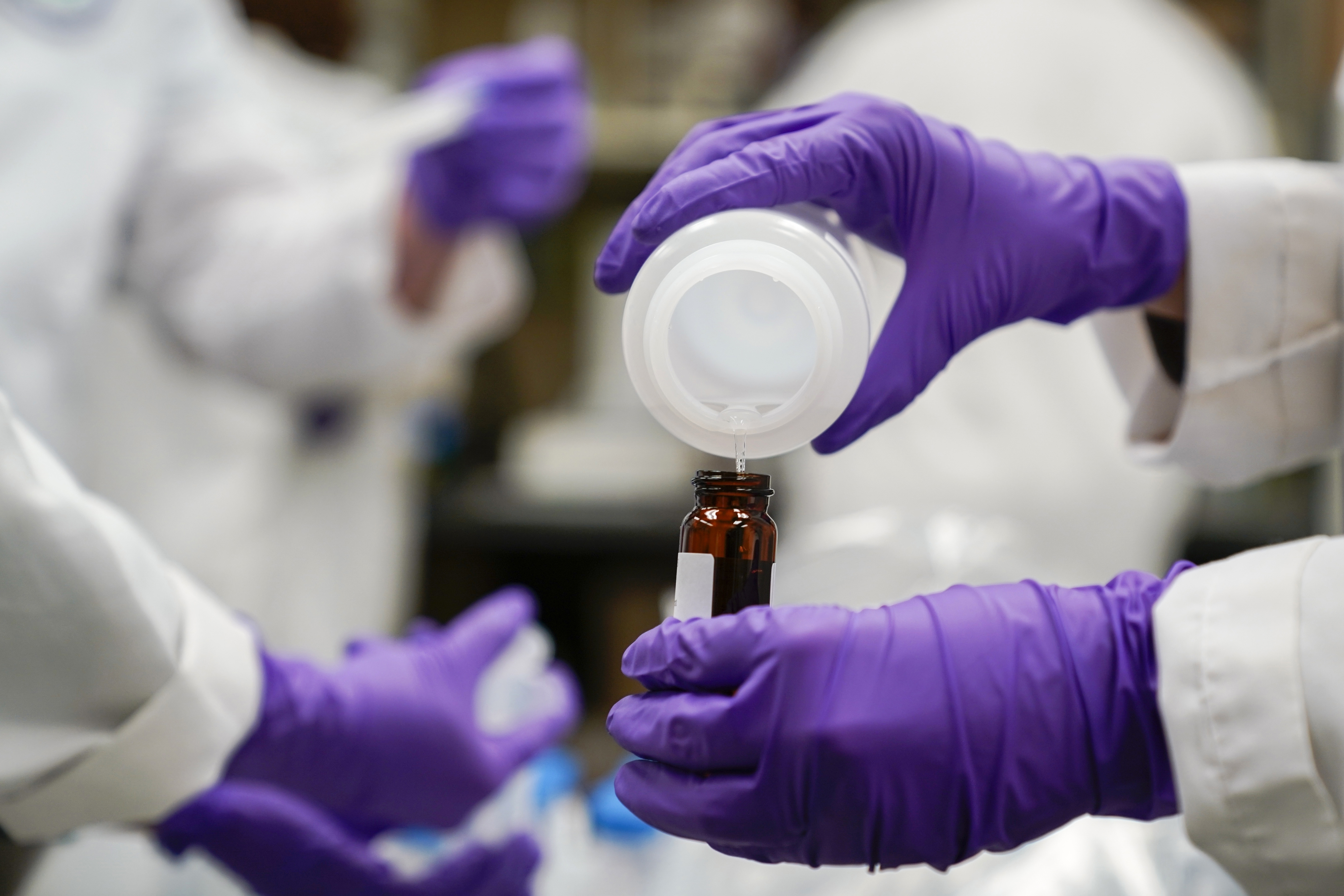 Eva Stebel, water researcher, pours a water sample into a smaller glass container for experimentation as part of drinking water and PFAS research at the U.S. Environmental Protection Agency Center For Environmental Solutions and Emergency Response on Feb. 16, 2023, in Cincinnati.<br />(Joshua A. Bickel / AP Photo)