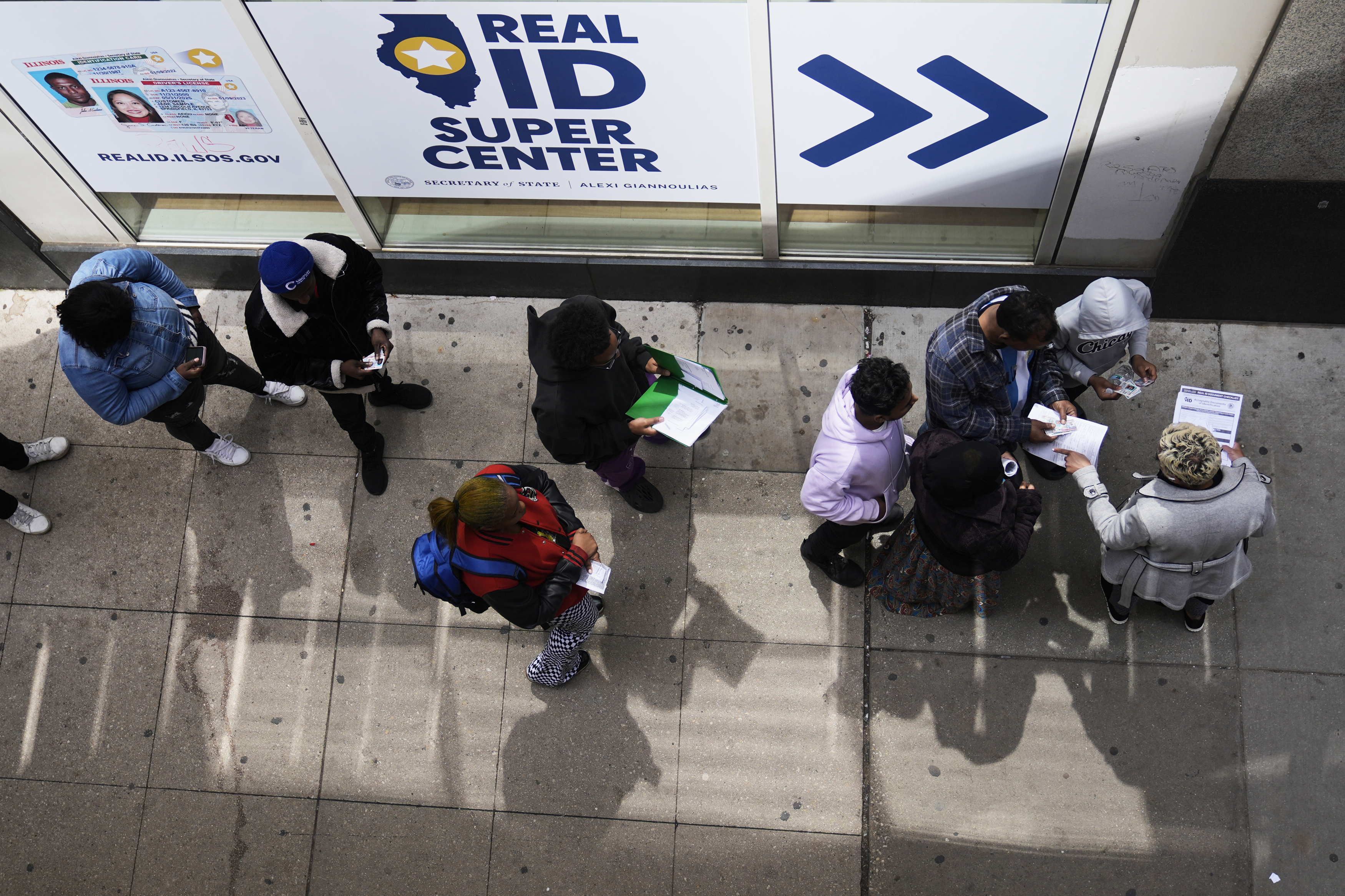 An employee (right) checks on necessary documents as people line up to apply for Real ID at a Real ID Supercenter in downtown Chicago, Tuesday, May 6, 2025.<br />(Kiichiro Sato / AP Photo)