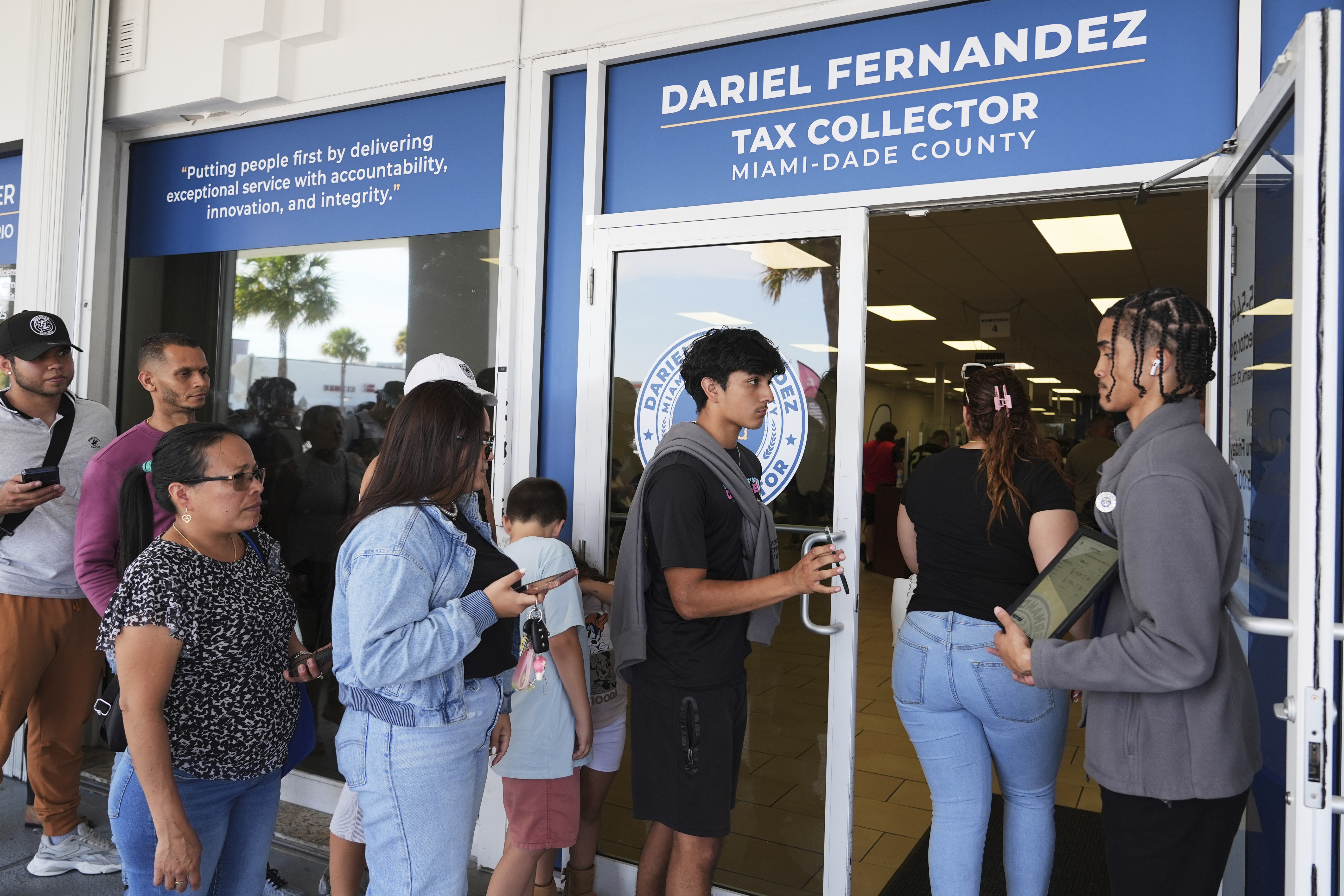 Customer Service representative Marlon Suarez (right) monitors the doorway outside of a Miami-Dade County Office of the Tax Collector Tuesday, May 6, 2025, in Miami.<br />(Lynne Sladky / AP Photo)