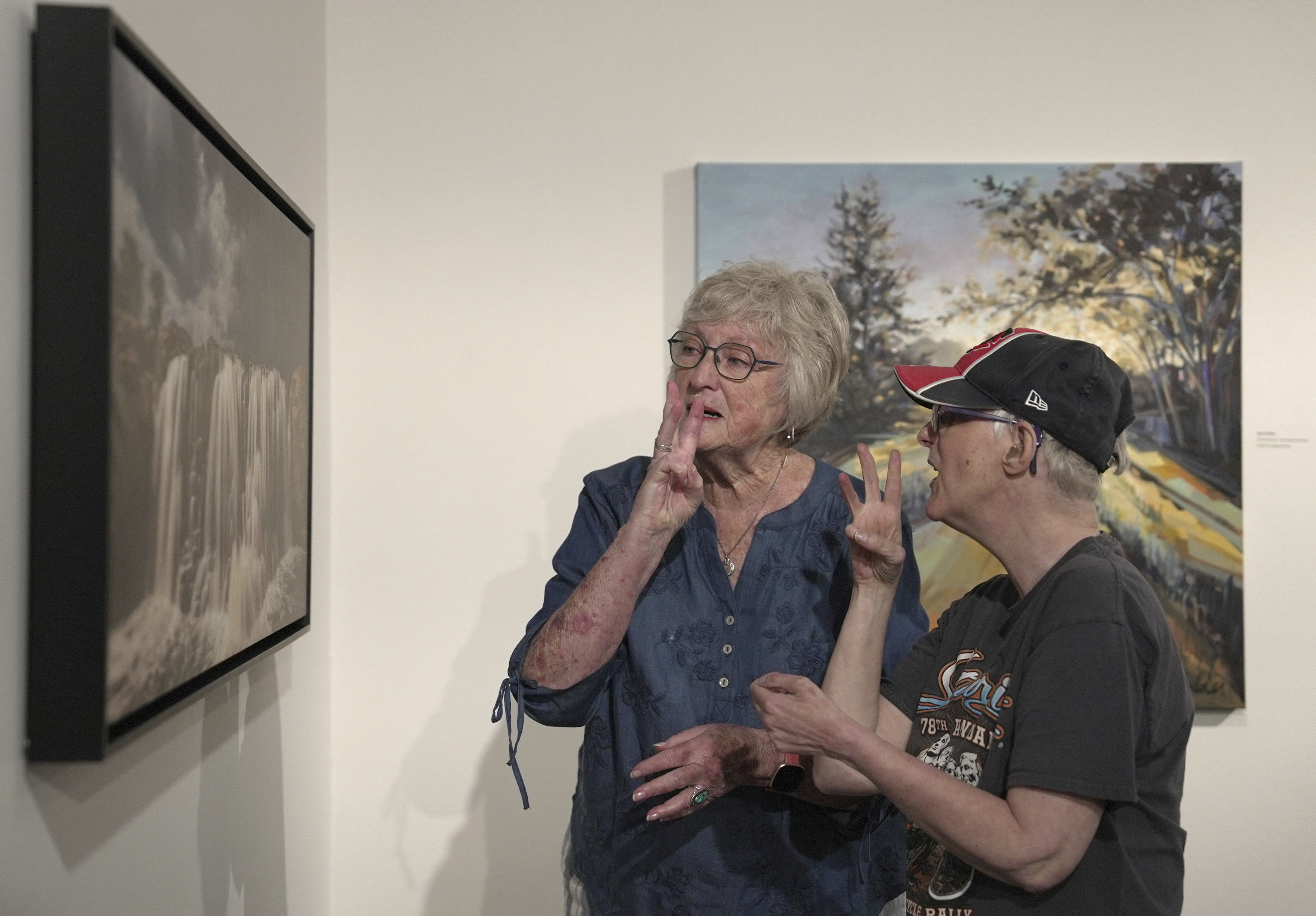 Janith Farnham signs &quot;water&quot; while she and her daughter, Jacque, look at an artwork of a waterfall at the Visual Arts Center at the Washington Pavilion in Sioux Falls, S.D., on May 20, 2025.<br />(Shelby Lum / AP Photo)