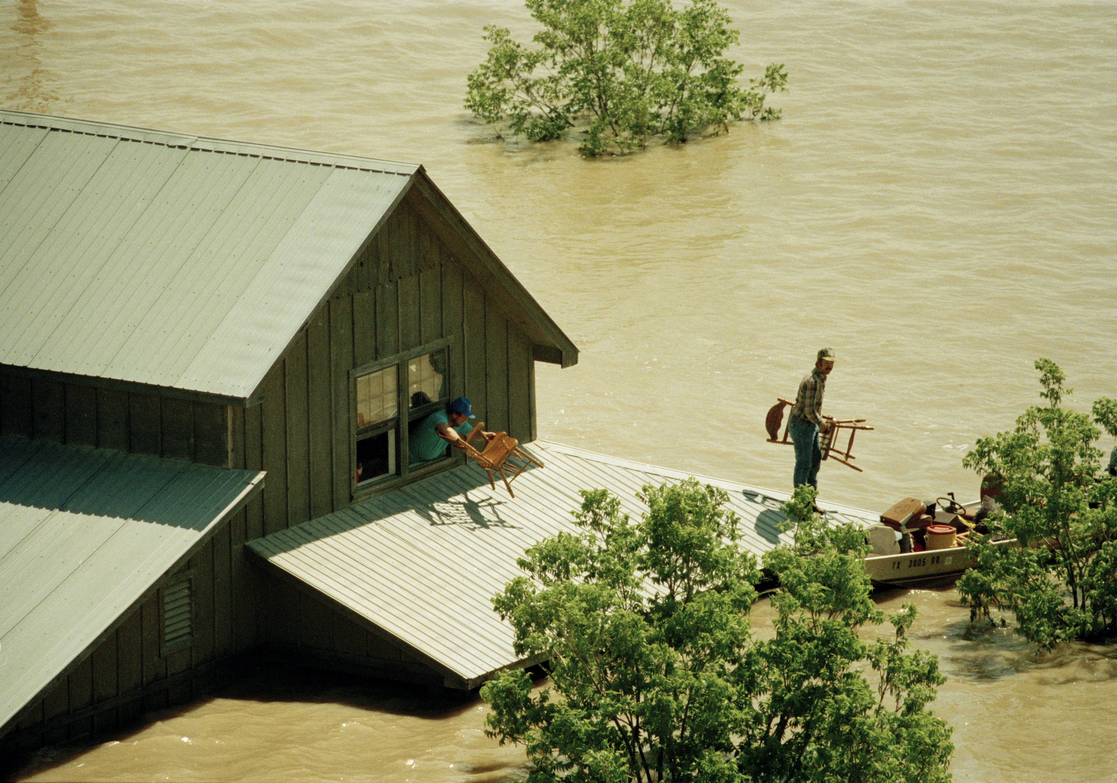 A family moves belongings out of a second floor window of a farm house to a waiting boat near Bristol, T.X., in Ellis County on Saturday, May 5, 1990.<br />(Pat Sullivan / AP Photo)