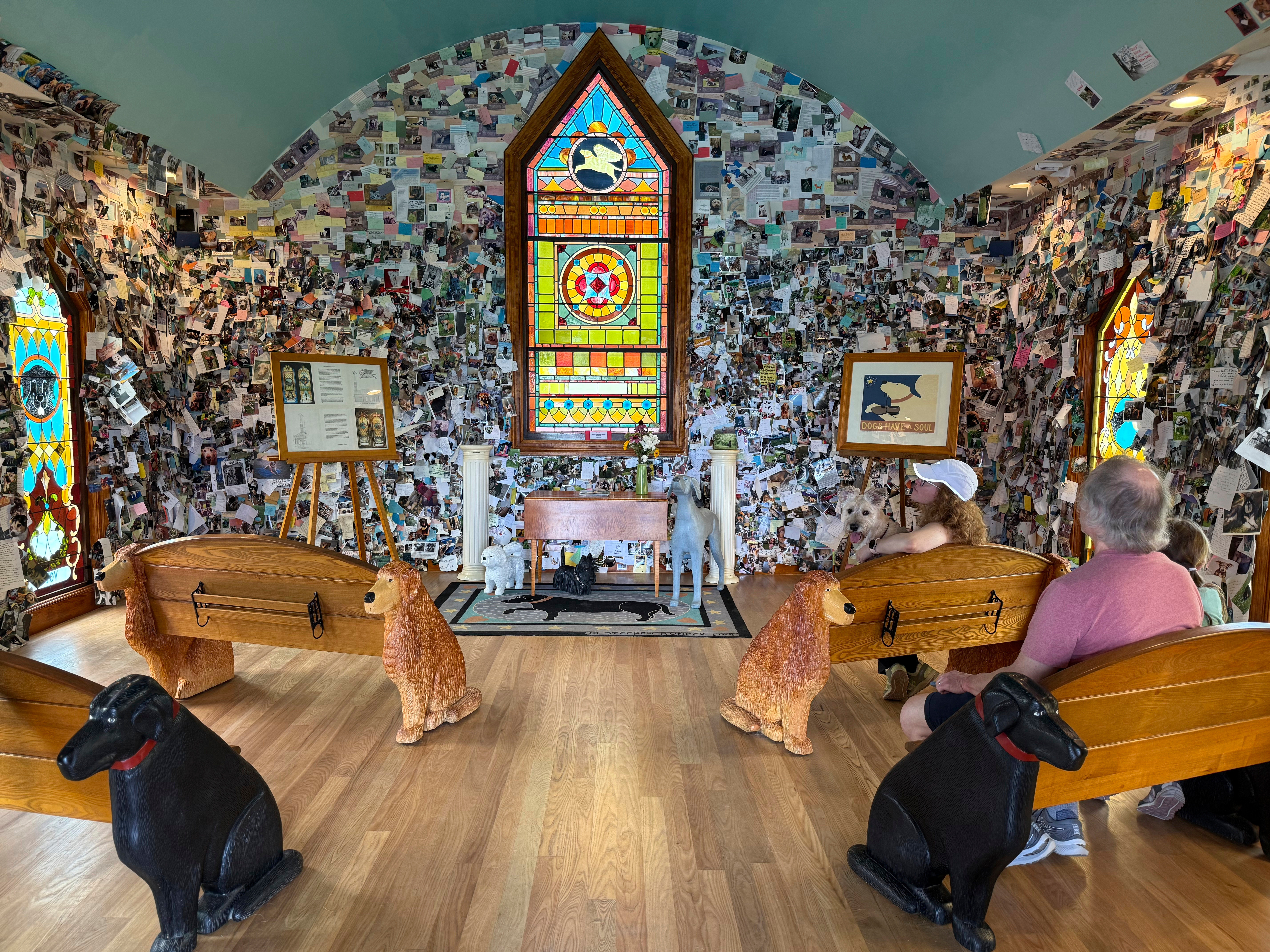 Visitors sit in the Dog Chapel at Dog Mountain, a 150-acre dog park created by Vermont folk artist Stephen Huneck, Thursday, Aug. 7, 2025, in St. Johnsbury, Vt.<br />(Amanda Swinhart / AP Photo)