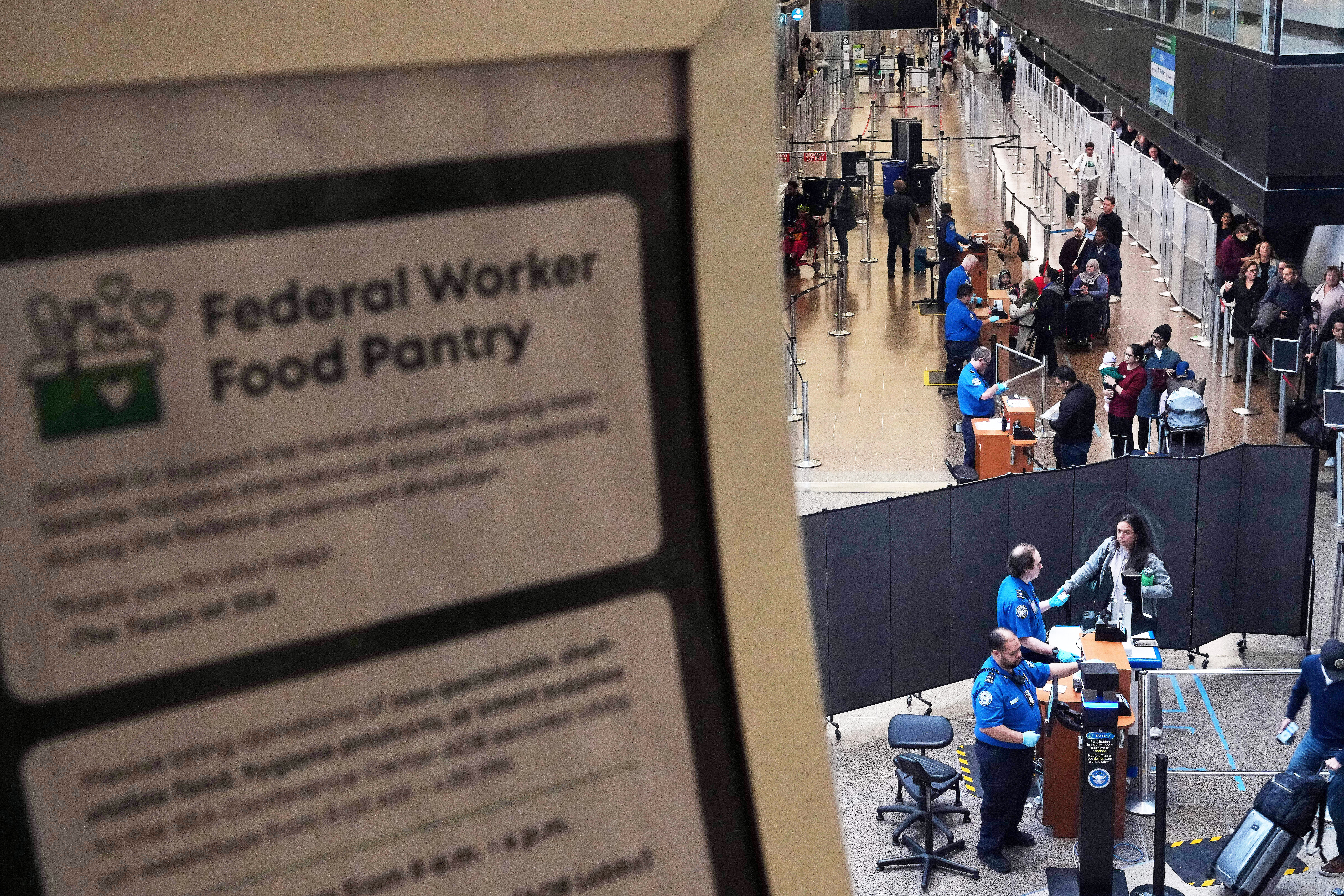 A sign for a food pantry for federal workers is seen as TSA agents check identification at a security checkpoint at Seattle-Tacoma International Airport, Thursday, Nov. 6, 2025, in SeaTac, Wash.<br />(Lindsey Wasson / AP Photo)