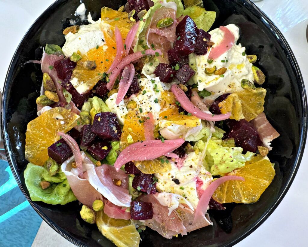 A colorful, fresh take on a brunch salad, the dish combines salty and sweet: marinated beets, prosciutto, burrata, orange slices, butter lettuce and a sprinkling of pistachios.<br />(Sarah Baker Hansen / Flatwater Free Press)
