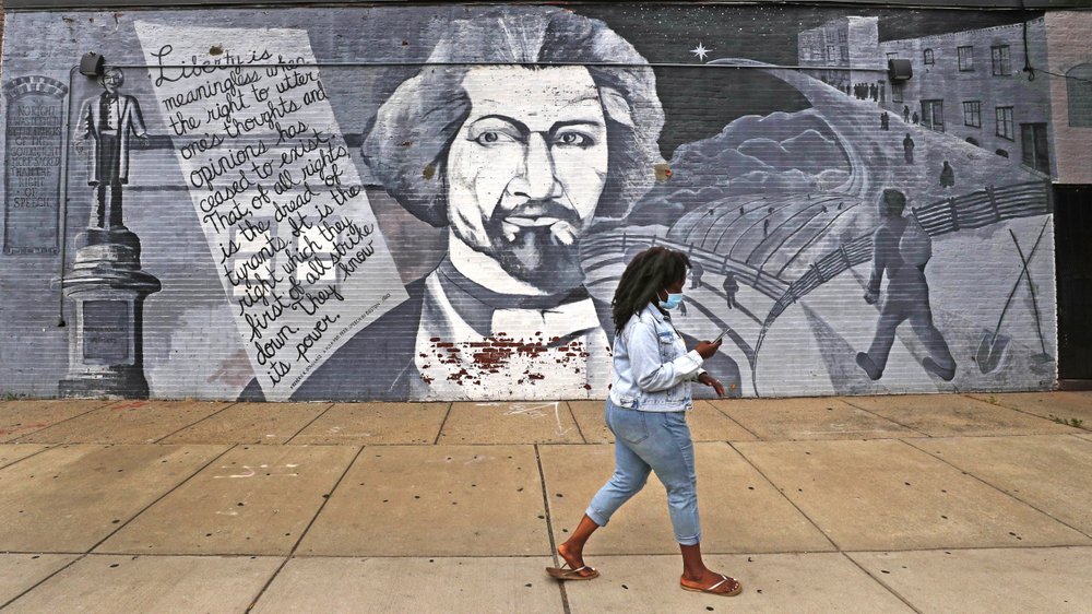 A woman walks past a mural in tribute to Frederick Douglass on the wall of the Black-owned Slade’s Bar and Grill in Boston on June 24, 2020. (AP)