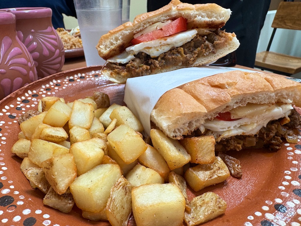 Flora Cafe’s huevo-wich is just what it sounds like: an egg sandwich made with a soft torta bun topped with two eggs, the choice of protein, tomatoes, refried beans, avocado, onion, smoky chipotle crema and cheese.<br />(Sarah Baker Hansen / Flatwater Free Press)