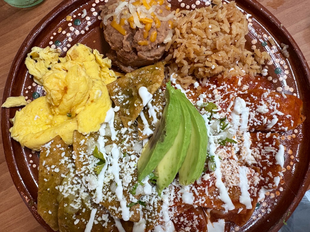Fried corn tortillas and scrambled eggs get gently tossed with green or red sauce (or a mix) and then topped with fresh cilantro, queso fresco, avocado and crema in chilaquiles, a Mexican brunch classic.<br />(Sarah Baker Hansen / Flatwater Free Press)