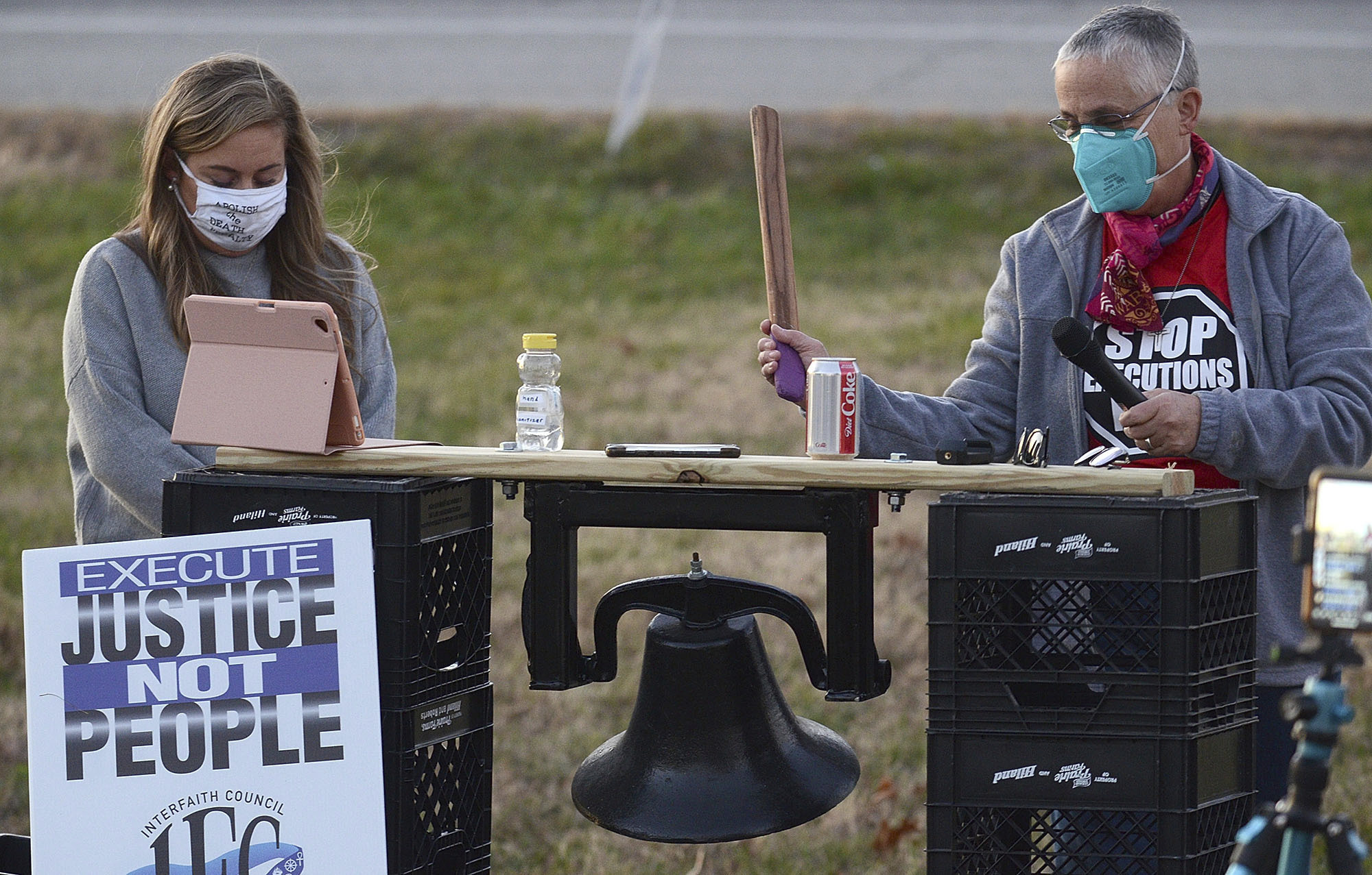 Sister Barbara Battista, right, tolls a bell before a minute of silence during the protest of the execution of Orlando Hall on Thursday, Nov. 19, 2020, across the street from the Federal Correctional Complex in Terre Haute, Ind. At left is attorney Ashley Kincaid-Eve. Orlando Hall, a man convicted of kidnapping and raping a 16-year-old Texas girl, was put to death later that day. (Joseph C. Garza/Tribune-Star via AP)