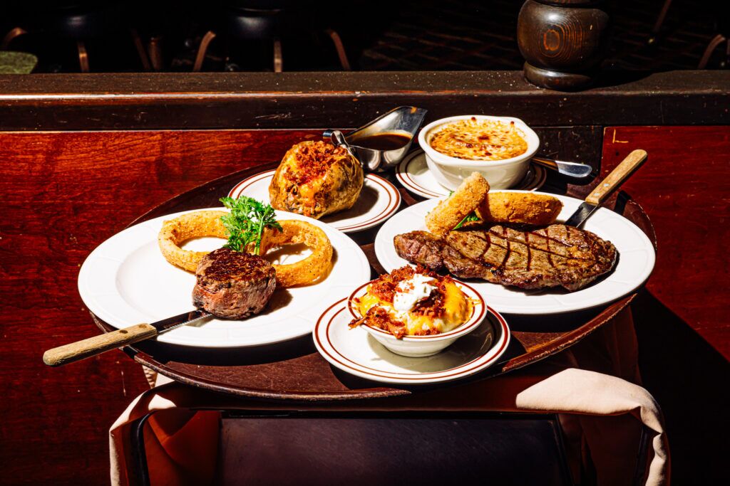 The Steak Town USA lineup pictured on a serving tray includes, from bottom left: a filet, a loaded baked potato, house-made mushroom gravy, French onion soup, a ribeye and a side of cowboy mashed potatoes.<br />(Joshua Foo / Flatwater Free Press)