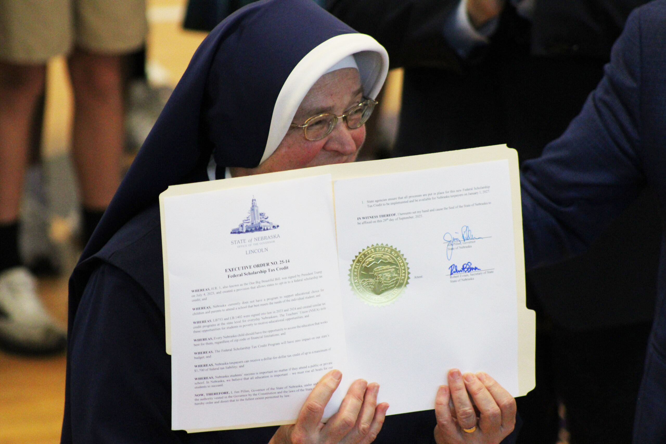 A St. Teresa Catholic School nun holding the Nebraska executive order that opts the state into a federal school choice tax credit program in Lincoln on Sep. 29, 2025.<br />(Juan Salinas II / Nebraska Examiner)