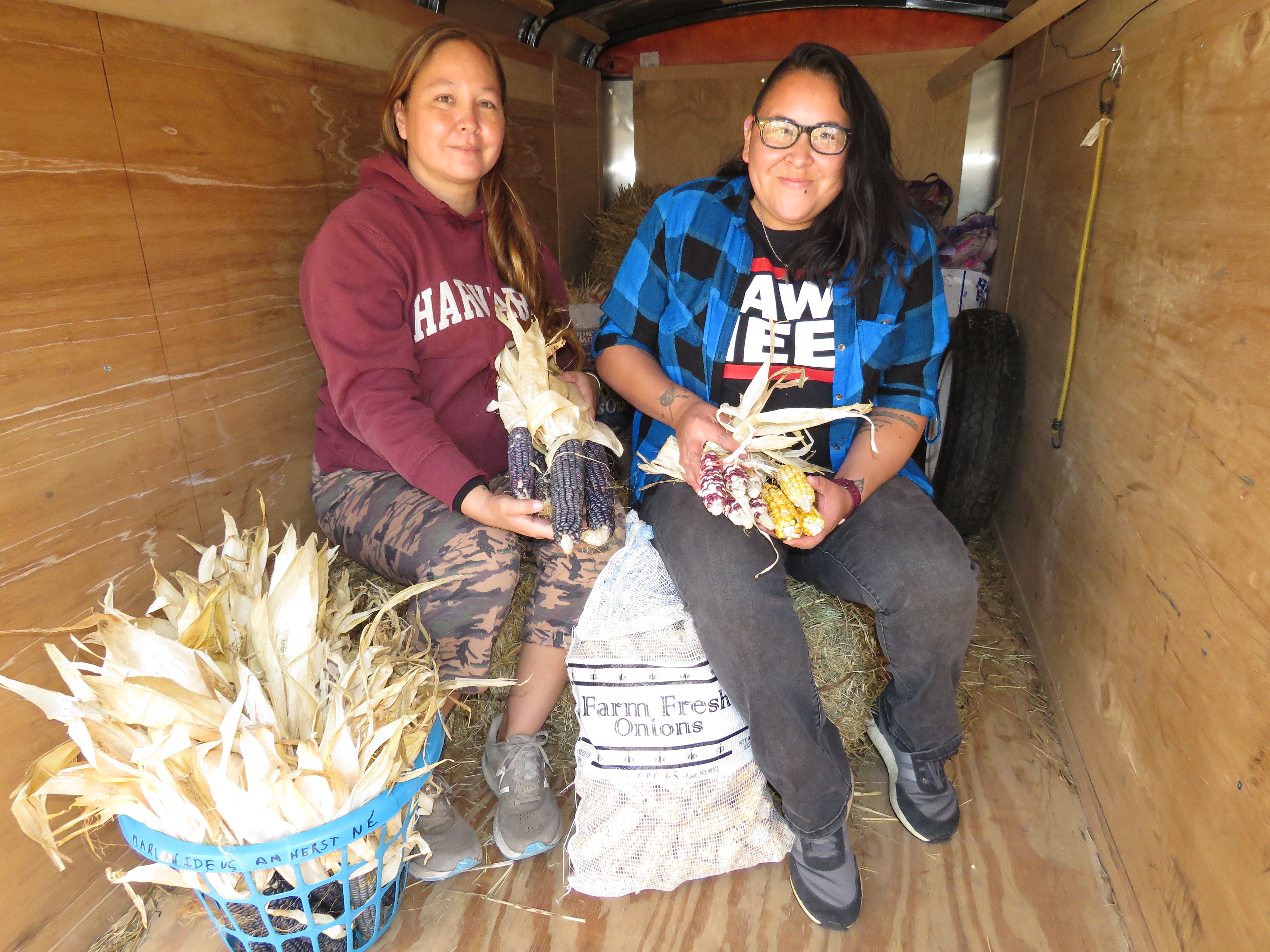 Electa Hare-RedCorn, left, who drove from Oklahoma to Hastings to collect the 2021 Pawnee corn grown in Nebraska, and Kahheetah Barnoskie, a UNL agronomy student, represent the next generation of Pawnee Seed Preservation Society leaders. The corn was transported to Pawnee, Okla., in this trailer on Oct. 13, 2021. (Lori Potter / Flatwater Free Press)