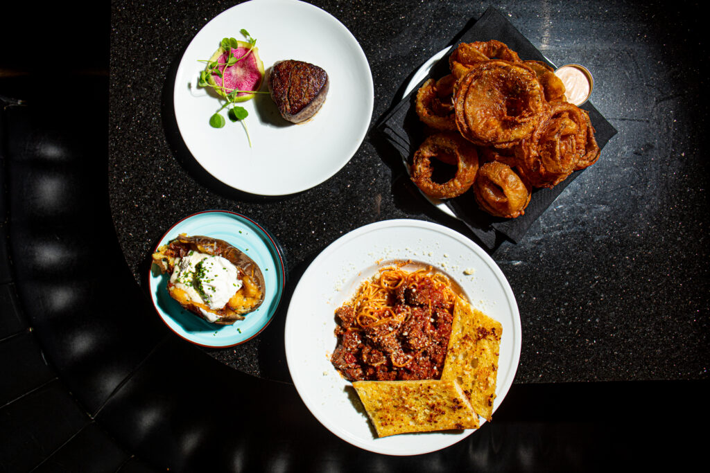 Several dishes on the Gorat’s menu include from top left a filet steak, house made onion rings, O.G. meat sauce and a loaded baked potato.<br />(Joshua Foo / Flatwater Free Press)