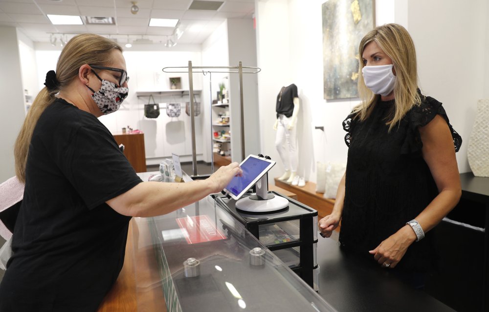 Monique Kursar, left, completes a purchase with Amy Witt, owner of the Velvet Window, in Dallas, May 13, 2020. For small retailers across the country, the coronavirus outbreak has turned an already challenging business environment into never-ending uncertainty. Witt might have 20 customers on a good day in her women’s clothing store, and then none the next. (AP)