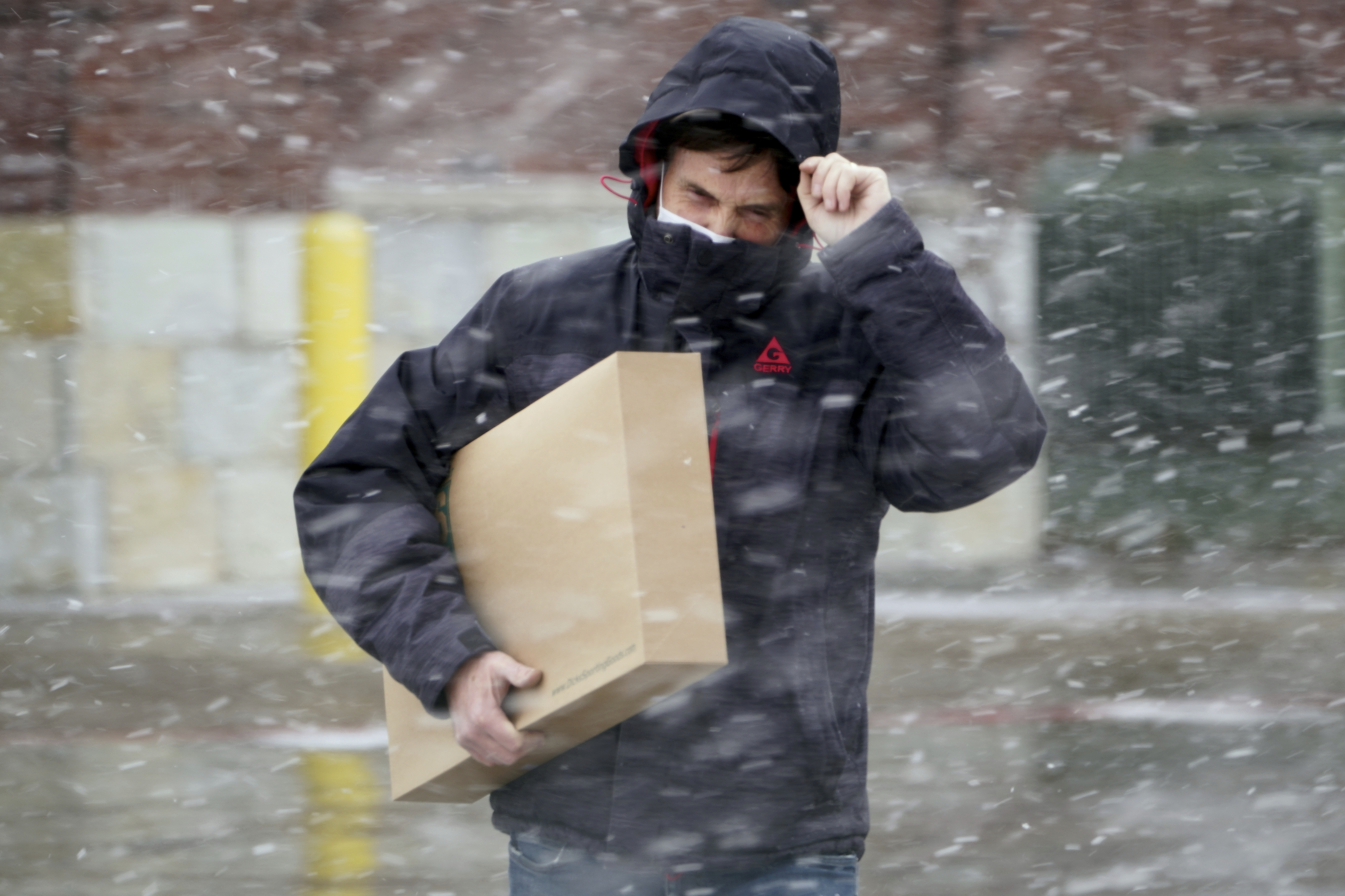 A shopper carries a box as he walks to his vehicle in blowing snow in Omaha., Wednesday, Dec. 23, 2020. Retailers saw a mixed bag in 2020 due to the pandemic. Many smaller stores struggled, banking on the holiday shopping season, while big box stores remained open and emphasized curbside pickup and delivery. Online retailers like Amazon grew their market share, too. (AP)