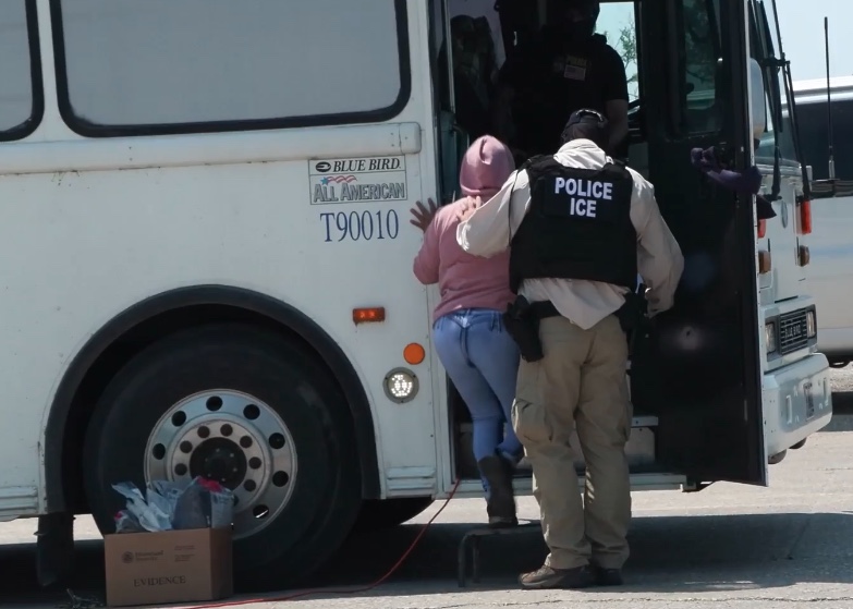 A worker is escorted to a bus headed to a detention center after she was apprehended at Glenn Valley Foods of Omaha during largest Nebraska immigration raid since President Donald Trump took office.<br />(Courtesy of U.S. Immigration and Customs Enforcement)