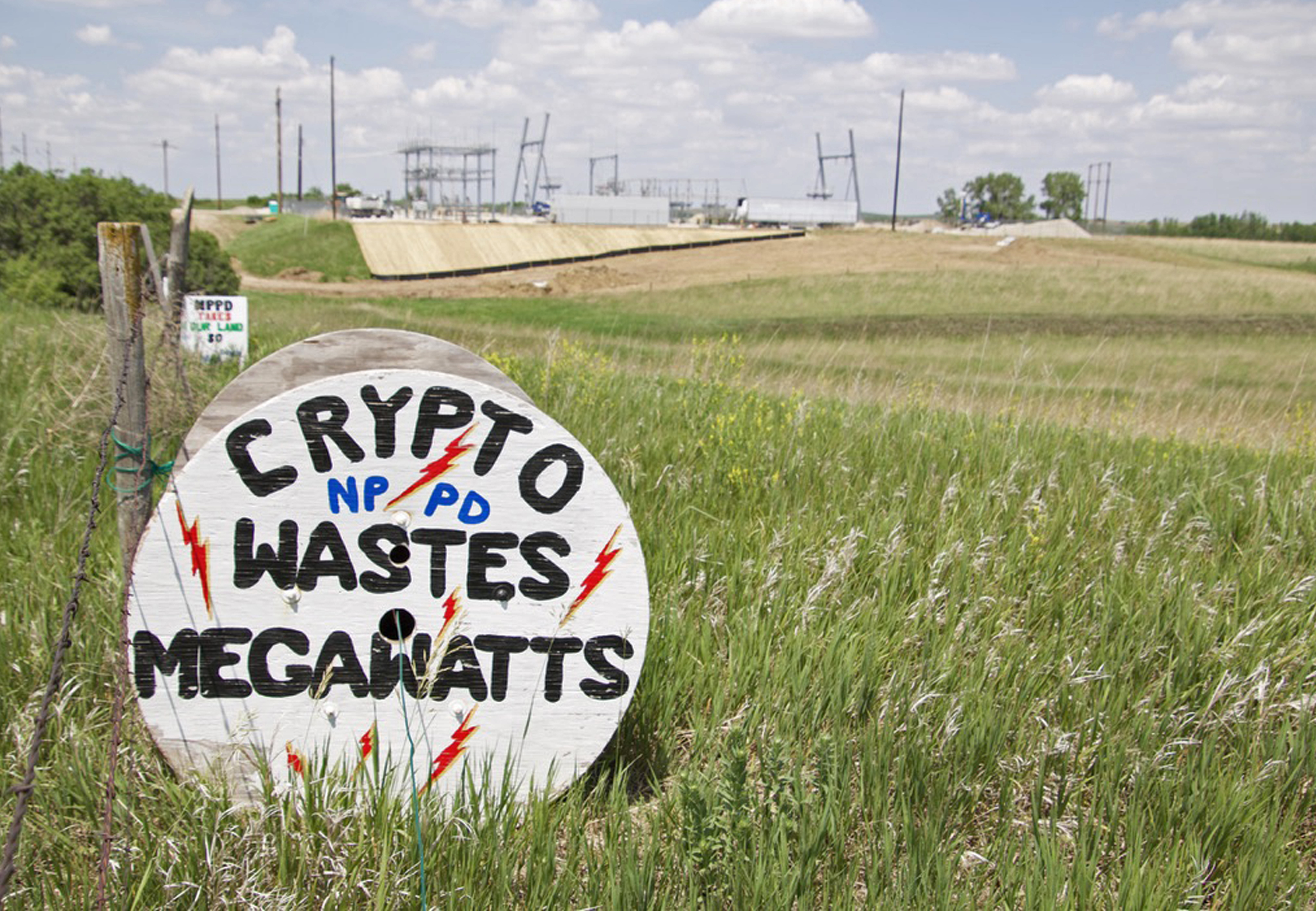 Signs painted by Stanton County resident Mary Wortmann sit across the road from Jigowatt’s crypto mining facility and south of the power substation that will soon feed it more energy.<br />(Jeremy Turley / Flatwater Free Press)