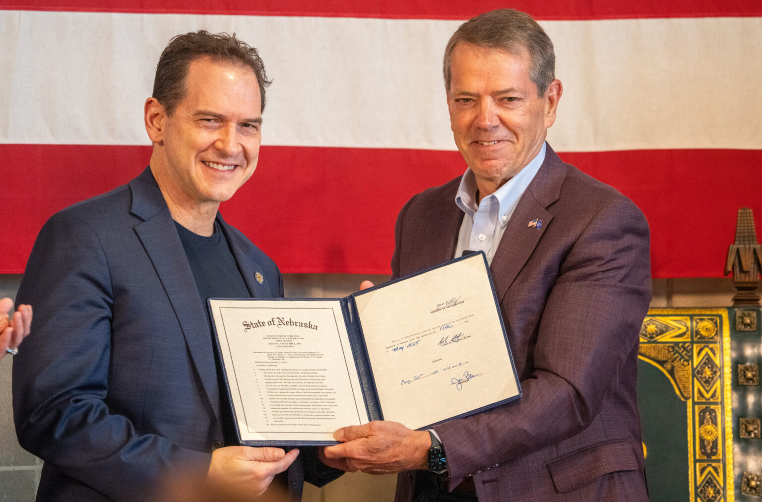 Gov. Jim Pillen (right) presents a signed version of Legislative Bill 383 to State Sen. Brian Hardin of Gering, a bill that included a provision from Hardin at Pillen’s request to outlaw child sexual abuse material generated with artifical intelligence, May 30, 2025.<br />(Zach Wendling / Nebraska Examiner)