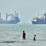 Children wade in the water with cargo ships at anchor in the background and a fisherman nearby, in the Strait of Hormuz off Bandar Abbas, Iran, Tuesday, June 30, 2026. 
(Amirhosein Khorgooi / ISNA via AP)