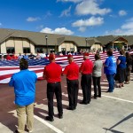 A dedication event for the Dunham House in Omaha, a long-term assisted living facility for veterans severely maimed in combat, kicked off Friday with a flag ceremony. The 30-unit residential complex is in the background. 
(Cindy Gonzalez / Nebraska Examiner)
