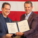 Gov. Jim Pillen (right) presents a signed version of Legislative Bill 383 to State Sen. Brian Hardin of Gering, a bill that included a provision from Hardin at Pillen’s request to outlaw child sexual abuse material generated with artifical intelligence, May 30, 2025. 
(Zach Wendling / Nebraska Examiner)