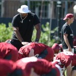 A University of Oklahoma football coach helps players stretch during practice on Aug. 4, 2023.
(Kyle Phillips / Oklahoma Voice)