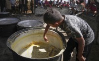 A boy scrapes leftovers from an empty pot after all the meals were distributed at a community kitchen in Khan Younis, southern Gaza Strip, Wednesday, May 14, 2025. 
(Abdel Kareem Hana / AP Photo)