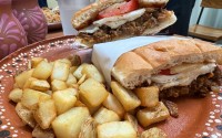 Flora Cafe’s huevo-wich is just what it sounds like: an egg sandwich made with a soft torta bun topped with two eggs, the choice of protein, tomatoes, refried beans, avocado, onion, smoky chipotle crema and cheese. 
(Sarah Baker Hansen / Flatwater Free Press)