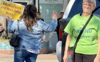 Rallygoers wave at passing cars that honk and give thumbs up to the “Stand in Solidarity” event Thursday afternoon in South Omaha.
(Cindy Gonzalez / Nebraska Examiner)