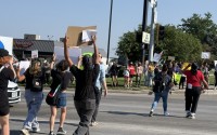 Protesters wave signs and chant near 33rd and L Streets in Omaha on Tuesday after a raid of an Omaha-area food plant. 
(Cindy Gonzalez / Nebraska Examiner)