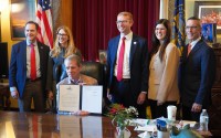 Nebraska Gov. Jim Pillen, seated (at center) holds up a newly signed executive order barring state health officials from diverting federal survivor benefits for youths in foster care to cover the costs of their care, Jan. 27, 2026. 
(Courtesy of Nebraska Department of Health and Human Services)