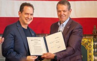 Gov. Jim Pillen (right) presents a signed version of Legislative Bill 383 to State Sen. Brian Hardin of Gering, a bill that included a provision from Hardin at Pillen’s request to outlaw child sexual abuse material generated with artifical intelligence, May 30, 2025. 
(Zach Wendling / Nebraska Examiner)