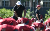 A University of Oklahoma football coach helps players stretch during practice on Aug. 4, 2023. 
(Kyle Phillips / Oklahoma Voice)