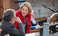 State Sen. Jane Raybould of Lincoln talks with state Sen. Stan Clouse of Kearney before debate on her priority bill to amend voter-approved annual increases to the state’s minimum wage, March 31, 2025. 
(Zach Wendling / Nebraska Examiner)