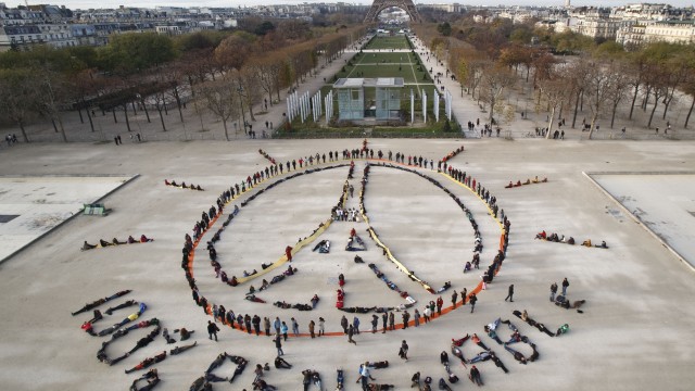 Environmentalist activists form a human chain representing the peace sign and the spelling out "100% Renewable", on the side line of the COP21, United Nations Climate Change Conference near the Eiffel Tower in Paris on Dec. 6, 2015. 
(Michel Euler / AP Photo)