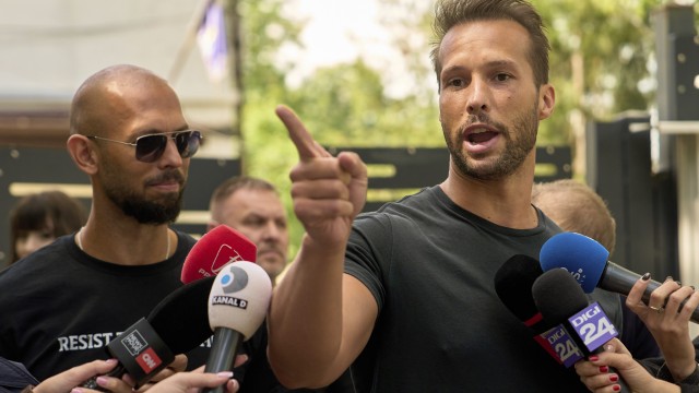 Andrew Tate (left) watches his brother Tristan speak, outside a police station in Voluntari, Romania, Wednesday, May 21, 2025.
 (Vadim Ghirda / AP Photo)